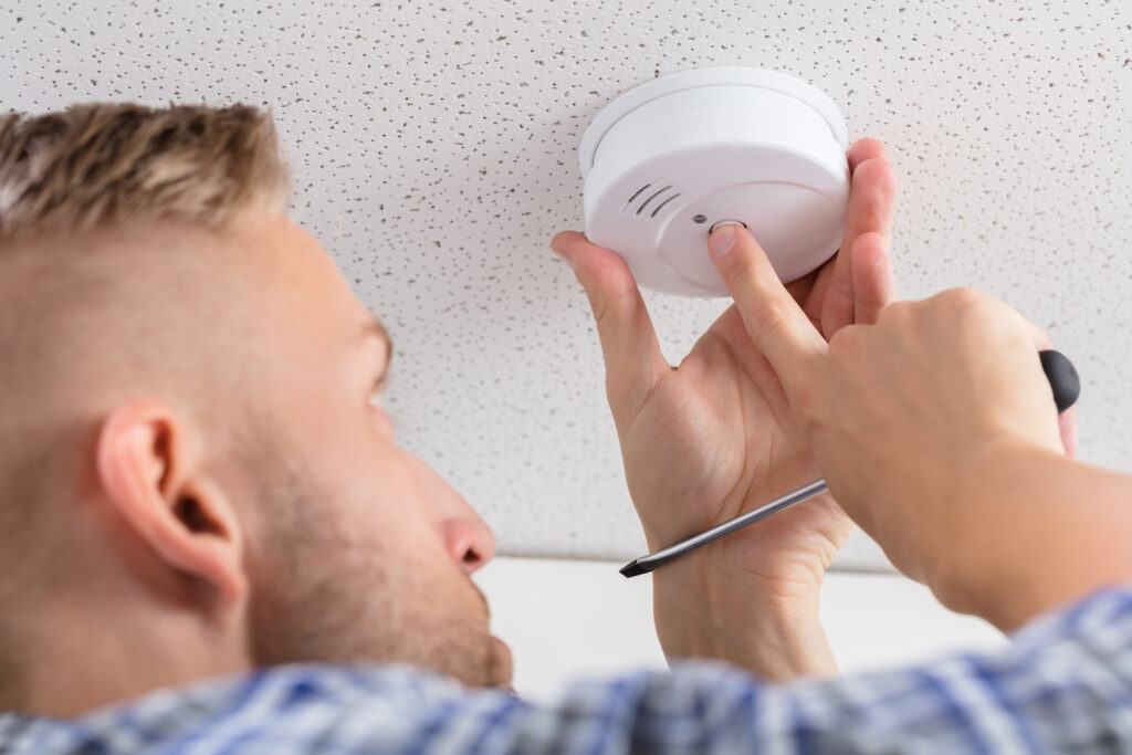 Picture of a tradesperson installing a smoke alarm