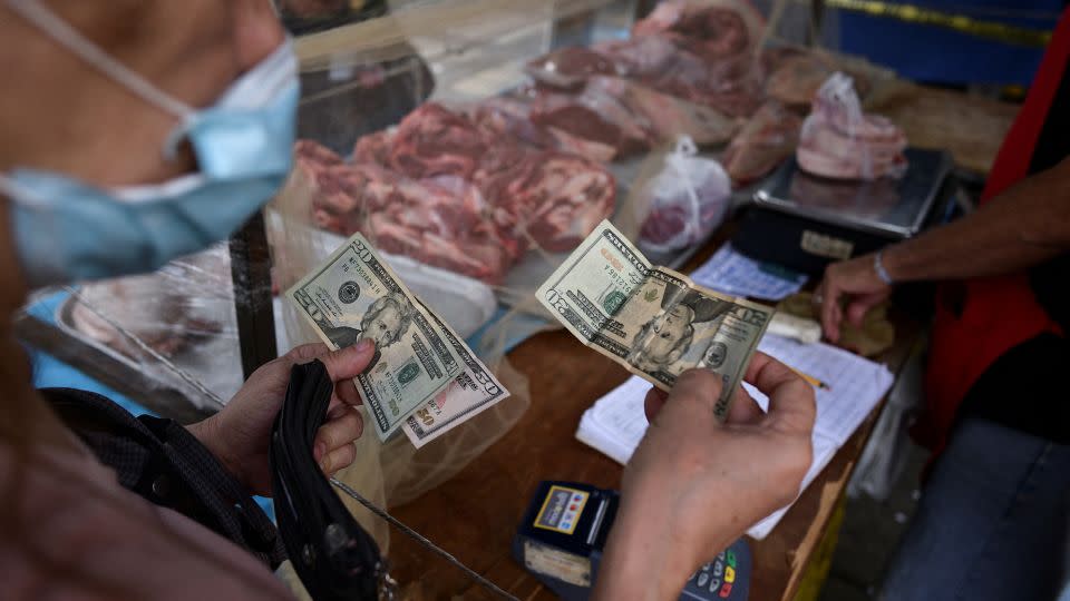 A customer pays for her purchase with U.S. dollar banknotes in an open-air fruit and vegetable market in Caracas, Venezuela February 10, 2023. - Gaby Oraa/Reuters