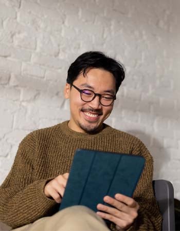 A man smiles as he looks at his tablet screen.