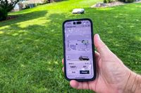 A person uses their smartphone to control the Ecovacs Goat A3000 LiDAR Robot Lawn Mower