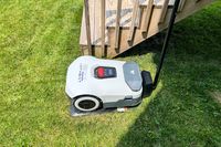 The ANTHBOT Genie 3000 Smart AI Robot Lawn Mower next to a staircase