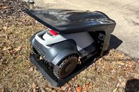 The Eufy Robot Lawn Mower E15 in its charging doc outdoors