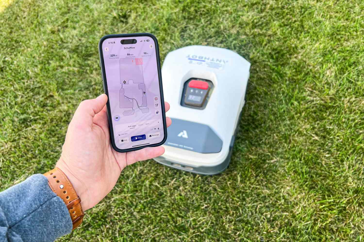 A person controls the ANTHBOT Genie 3000 Smart AI Robot Lawn Mower with their phone