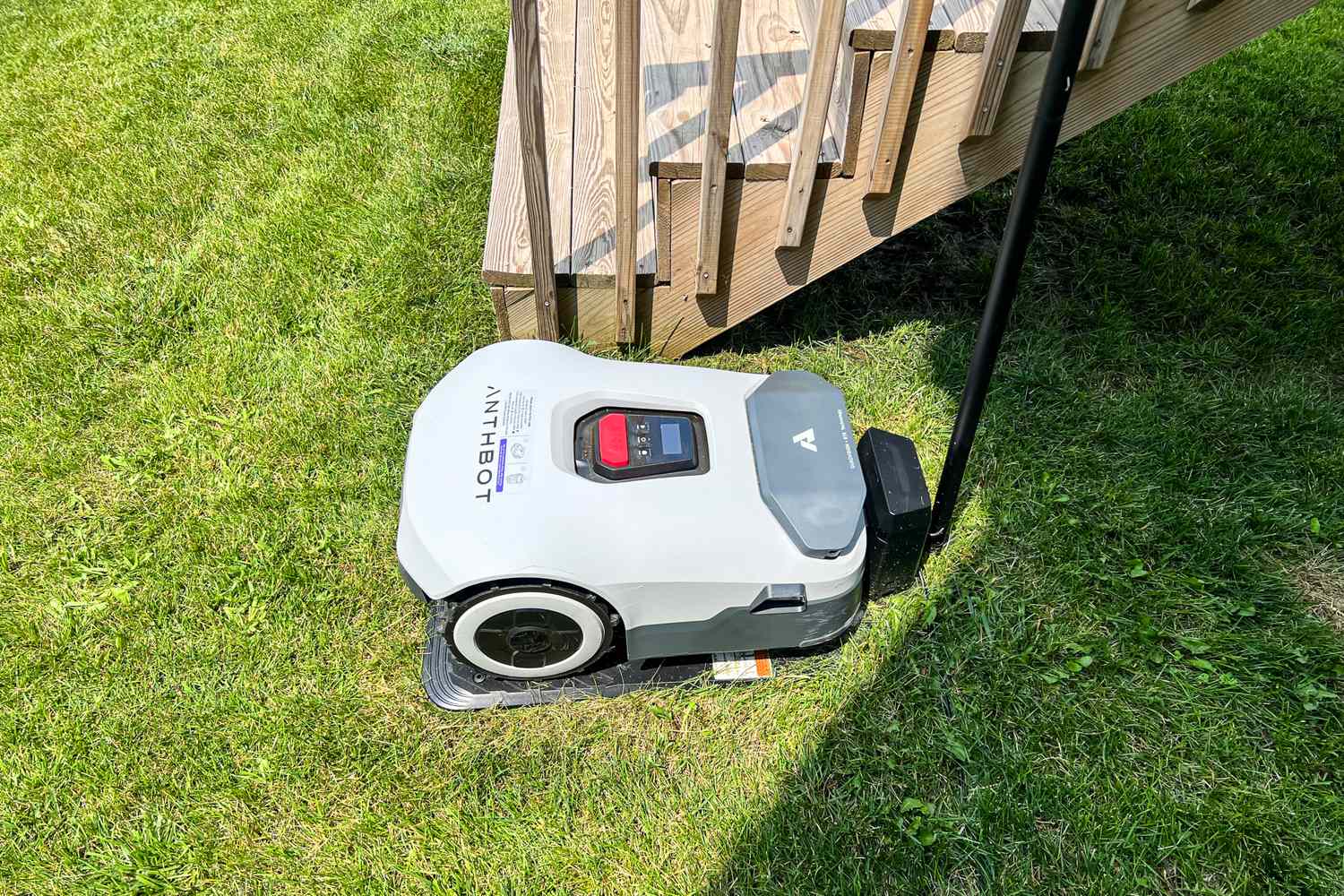 The ANTHBOT Genie 3000 Smart AI Robot Lawn Mower next to a staircase