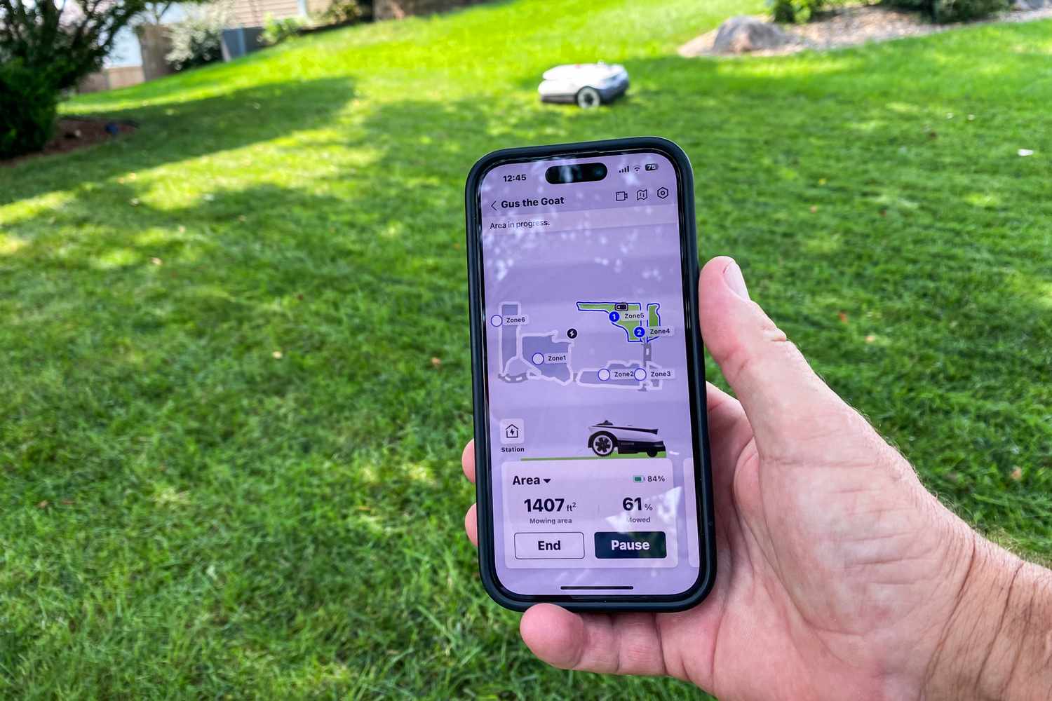 A person uses their smartphone to control the Ecovacs Goat A3000 LiDAR Robot Lawn Mower