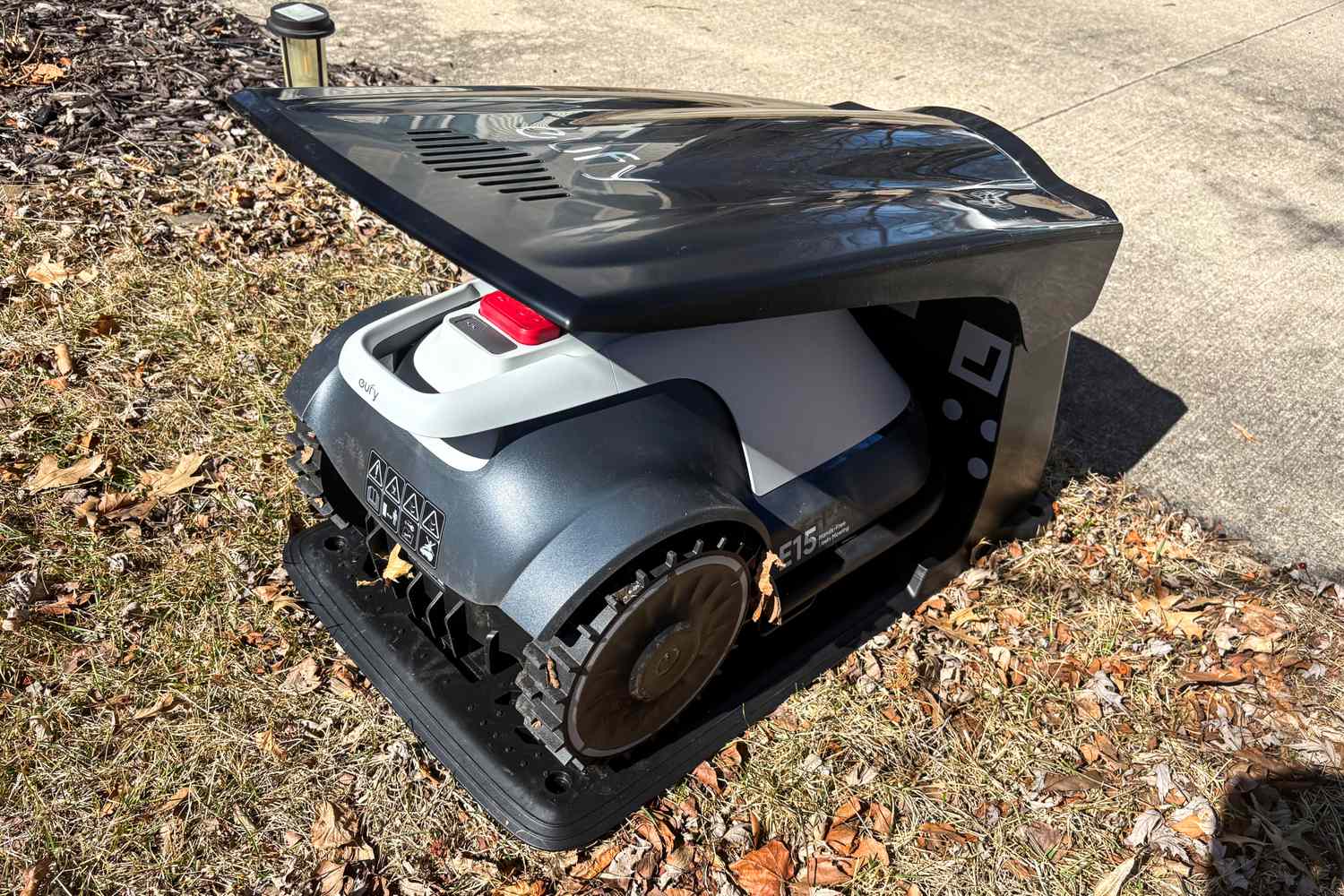 The Eufy Robot Lawn Mower E15 in its charging doc outdoors