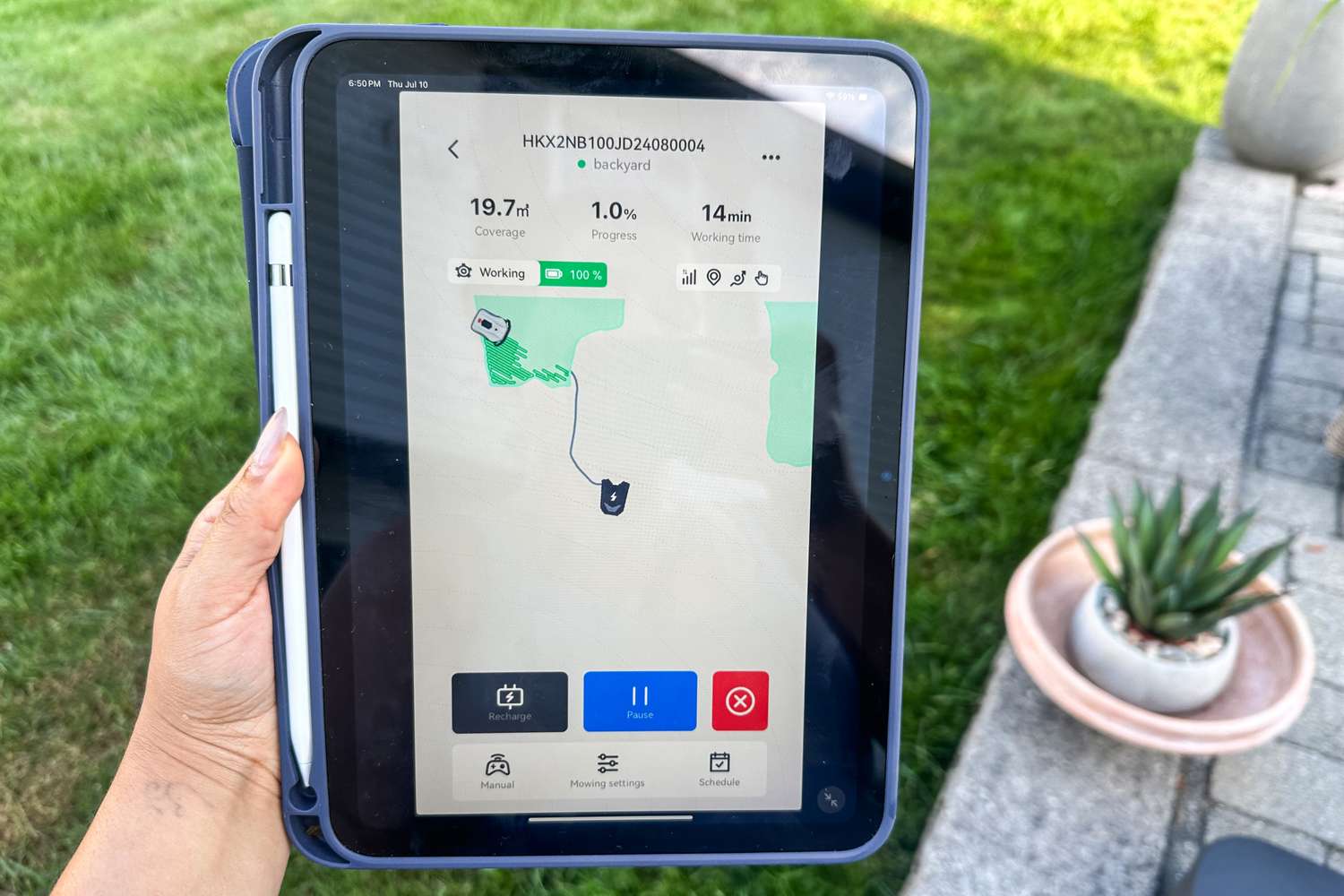 A person tracks the progress of the Hookii Neomow X Pro Robotic Lawn Mower on an iPad